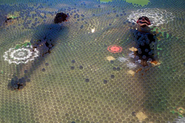 Patterns being projected on the ping pong ball surface while swimmers perform.