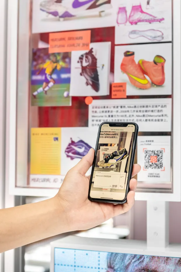 A phone running a Nike app in front of an informational poster.