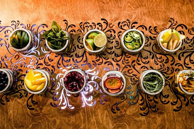 Cocktail ingredients in individual containers on a lit up table.